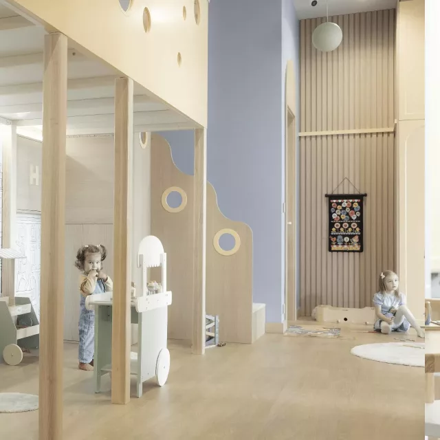 Enterijer čuvaonice Kids Club sa detetom koje se igra u pozadini