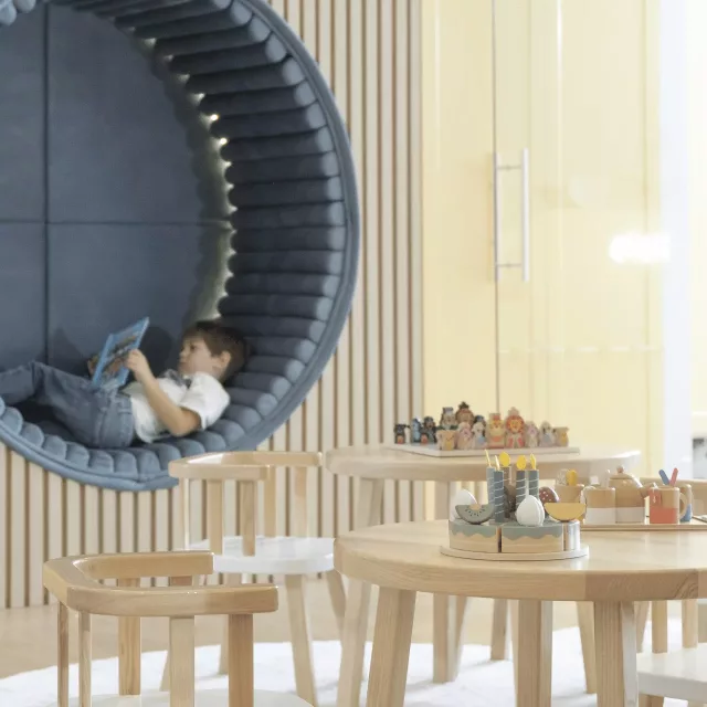 Dete koje leži i čita knjigu u delu za odmor čuvaonice Kids Club Beograda na vodi