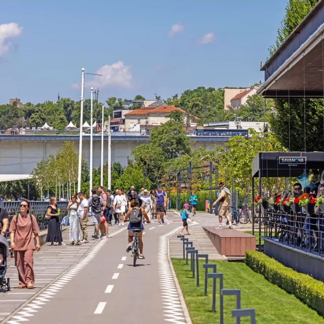 Ljudi šetaju Sava Promenada šetalištem, ispred Savanova restorana.