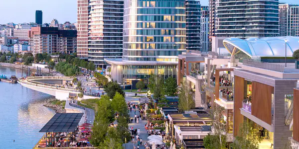 Ljudi šetaju Sava Promenadom, pored Galerije i Kule Beograd.